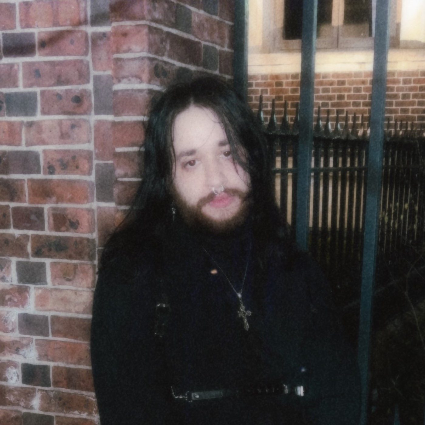 Portrait of durl against a brick wall and iron fence